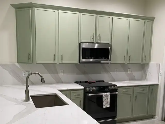 Sage green shaker kitchen with marble-look quartz counters and full-height quartz backsplash