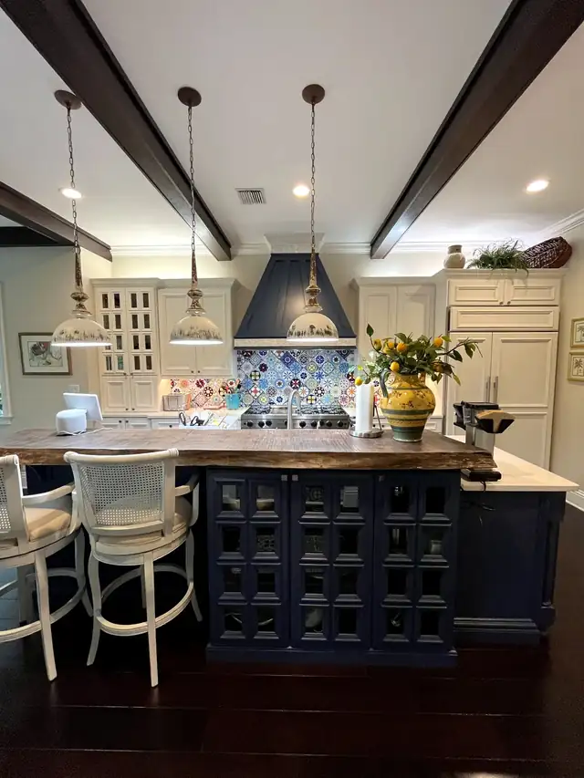 Refinished kitchen with an Indigo Baltic island, cream perimeter cabinets, butcher-block counter and blue patterned tile
