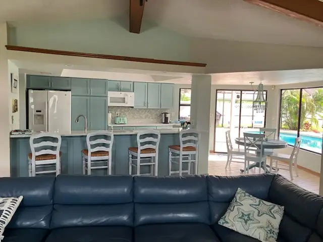 Kitchen refaced with Delft blue shaker doors, white counters and a breakfast bar that looks out to the pool
