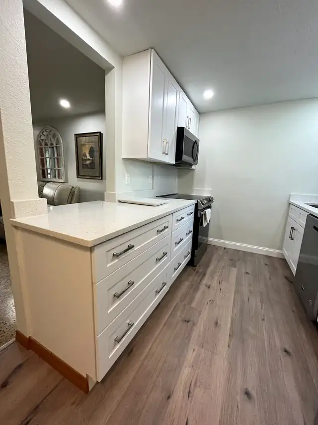 Opened-up Largo kitchen remodel with white shaker cabinets, white quartz counters and wide-plank vinyl floors