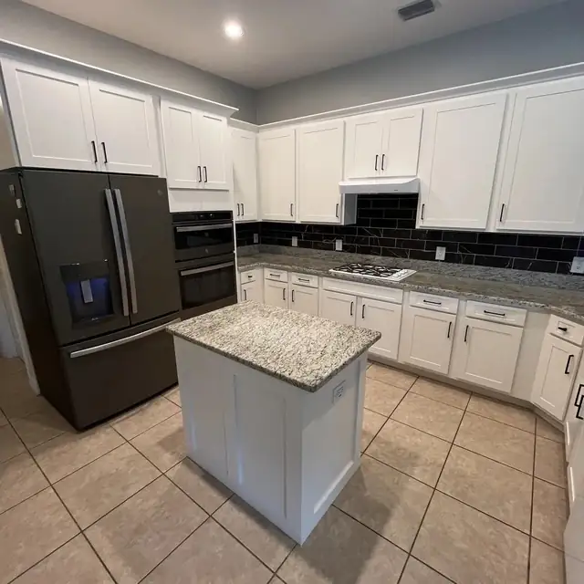 Wesley Chapel kitchen refaced with white shaker doors, a granite-topped island and dark subway tile backsplash
