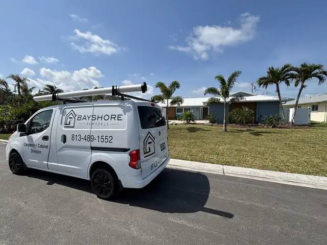 White Bayshore Remodels work van with the company logo and phone number parked on a palm-lined Tampa Bay street