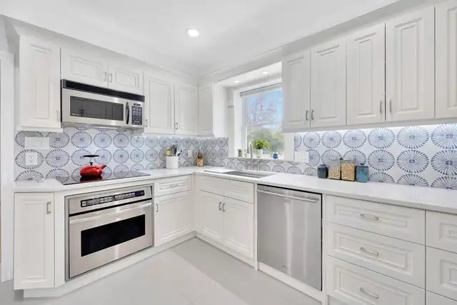 Redington Beach kitchen with white raised-panel cabinets and a blue and white patterned tile backsplash